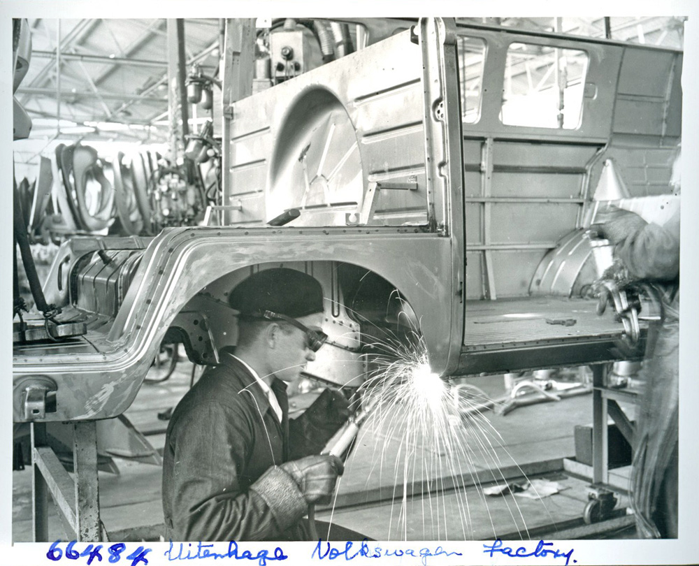 A worker is welding the wheel well on a Transporter body